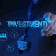 A_man_pointing_towards_the_word_INVESTMENT_accompanied_by_icons_representing_various_investment_sectors_f25ef2964a
